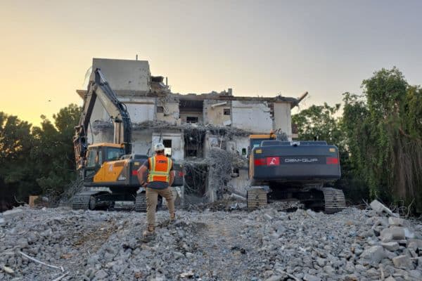 Dem-Quip excavator demolishing building at golden hour